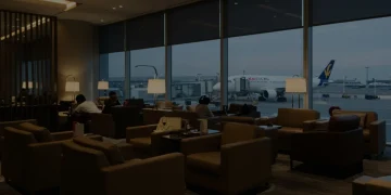 Pessoas relaxando em uma luxuosa sala VIP de aeroporto, com poltronas confortáveis e vista para a pista de pouso.